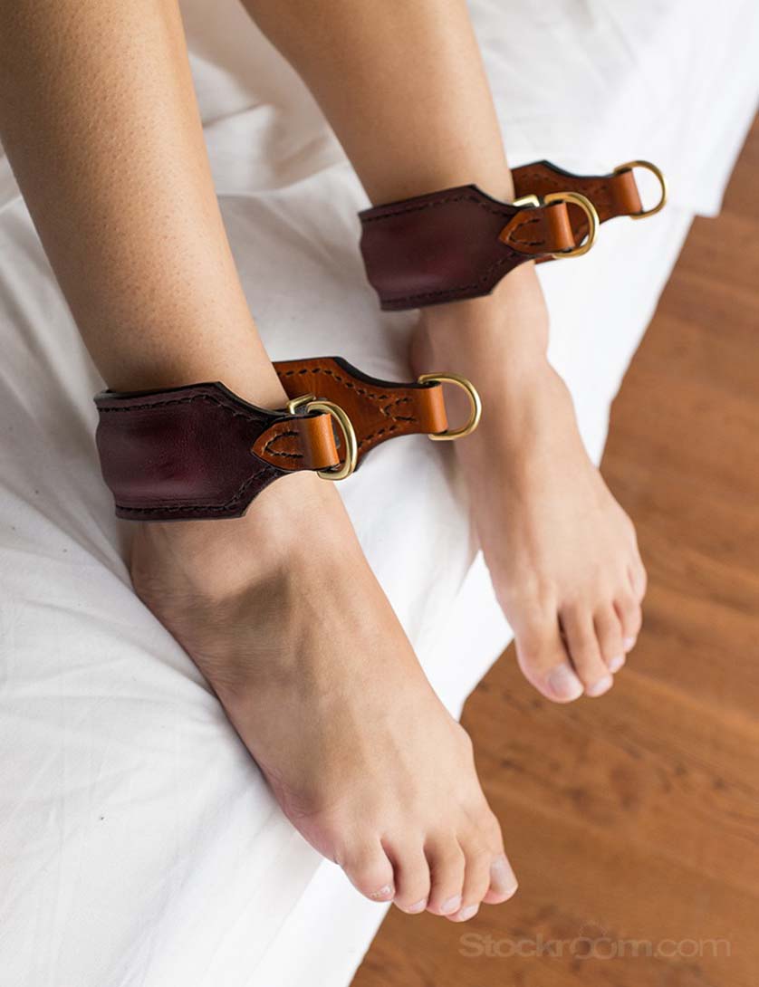 Nude girl wearing Burgundy/Saddle Tan Ankle Cuffs by Paraphilia. Exclusive bondage restraints from the stockroom.